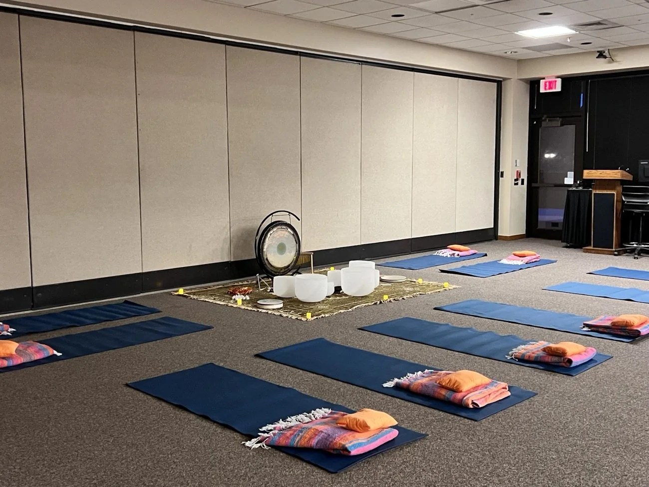 Mats and blankets arranged around singing bowls and a gong before a sound bath