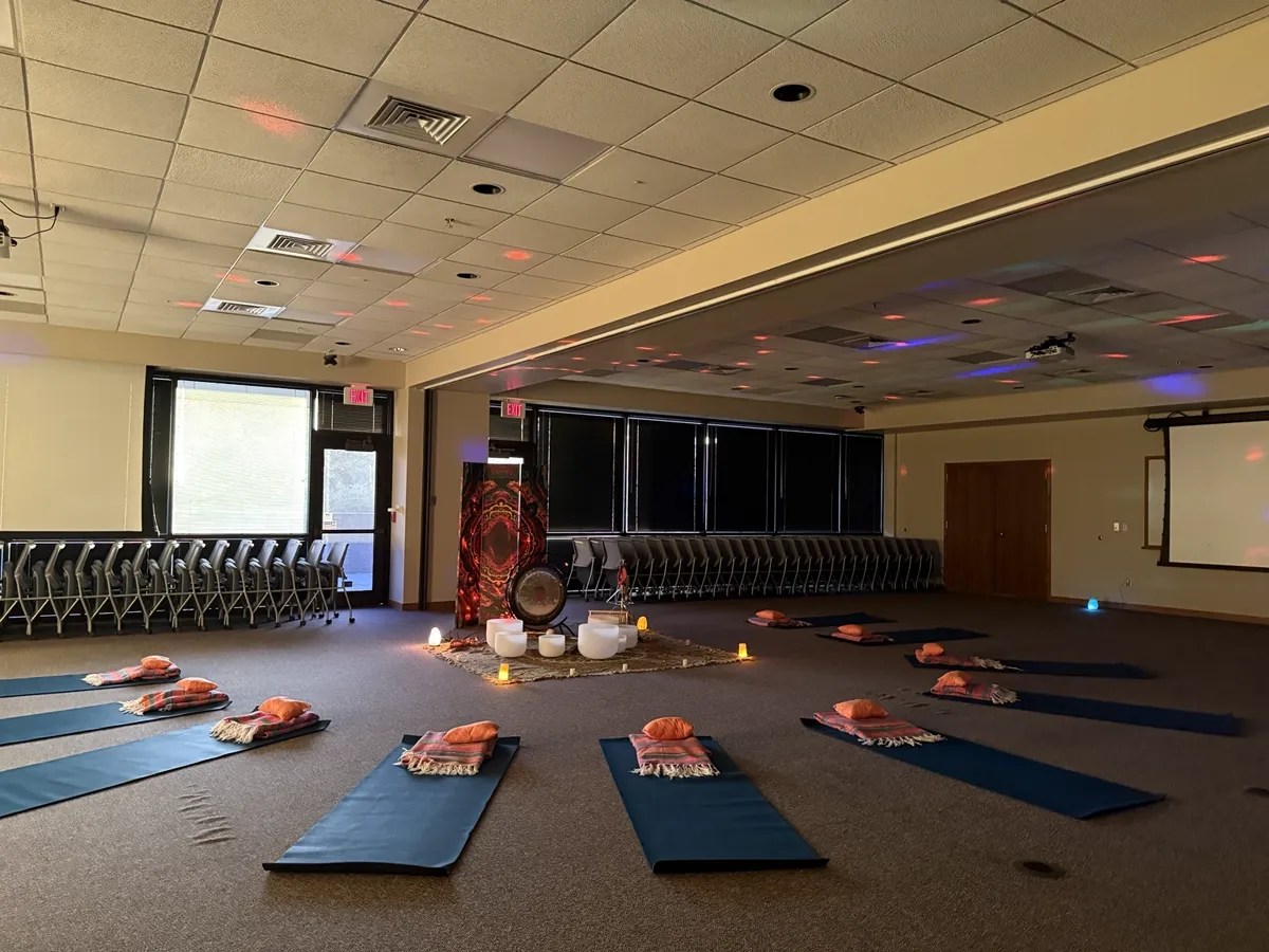 Sound bath mats set around a gong and singing bowls in a softly lit room
